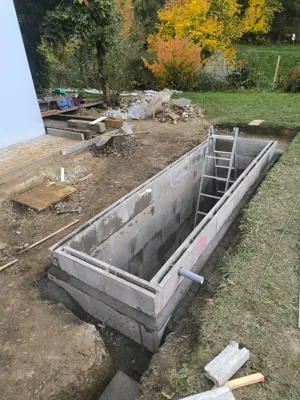 Nádrž u fasády domu, staveniště v plném provozu.